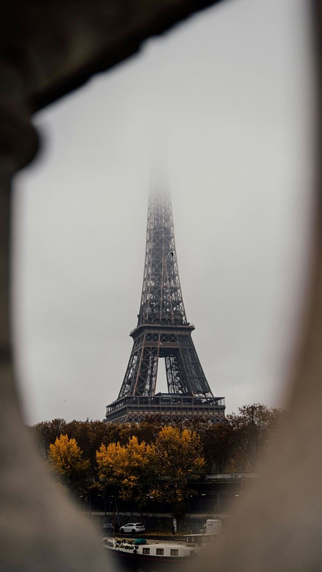 1290x2796 A view of the eiffel tower through a hole in a wal... -  iPhone Wallpaper