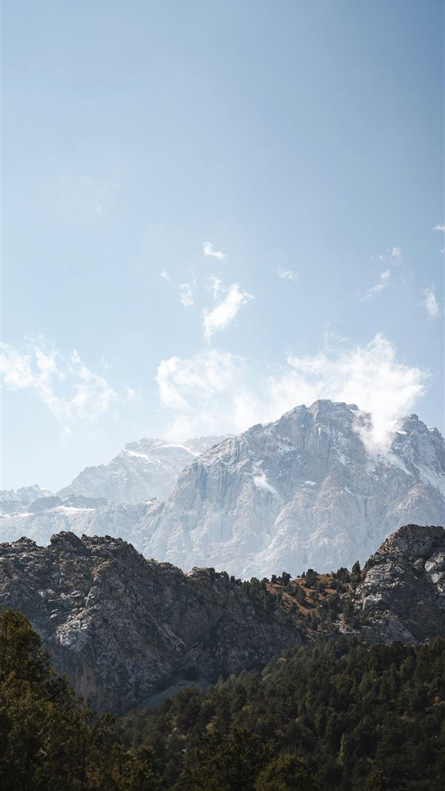 1290x2796 A view of a mountain range with trees in the foreg... -  iPhone Wallpaper