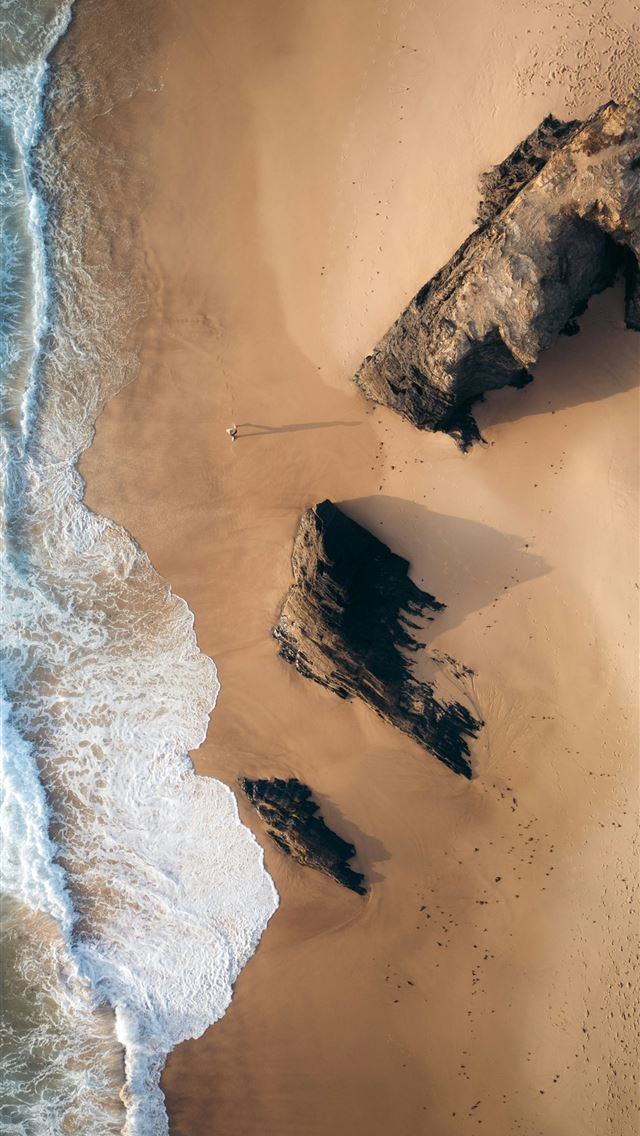 1290x2796 Waves gently wash over a sandy beach with rocks  -  iPhone Wallpaper