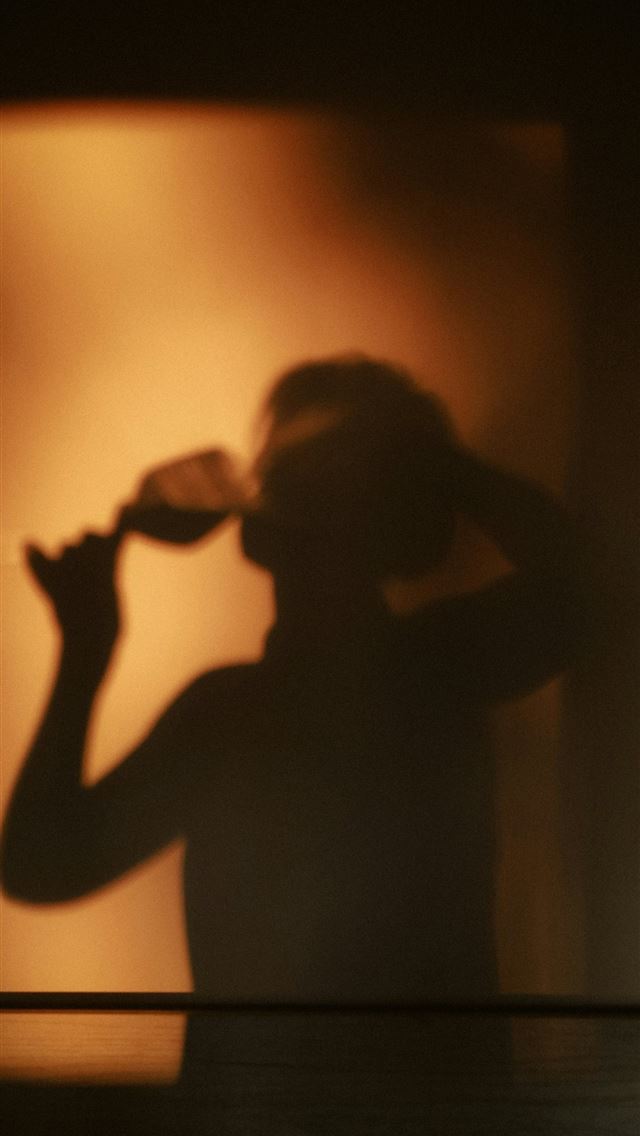 1290x2796 Shadow of person drinking wine against warm light -  iPhone Wallpaper