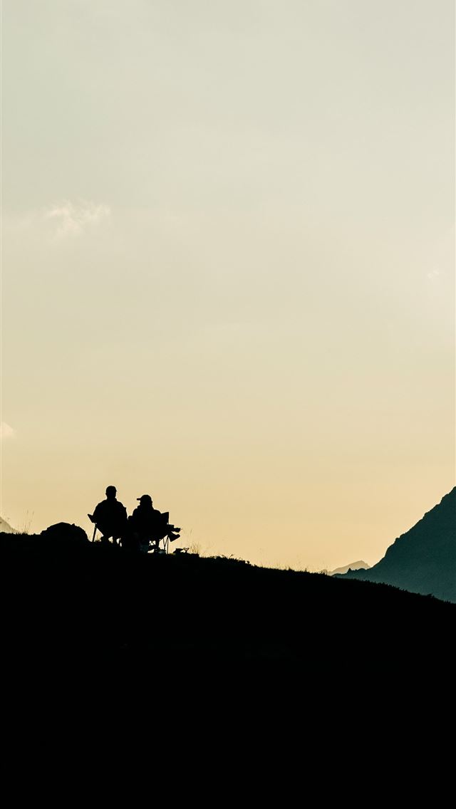 1290x2796 Two people silhouetted on a mountain ridge at suns... -  iPhone Wallpaper
