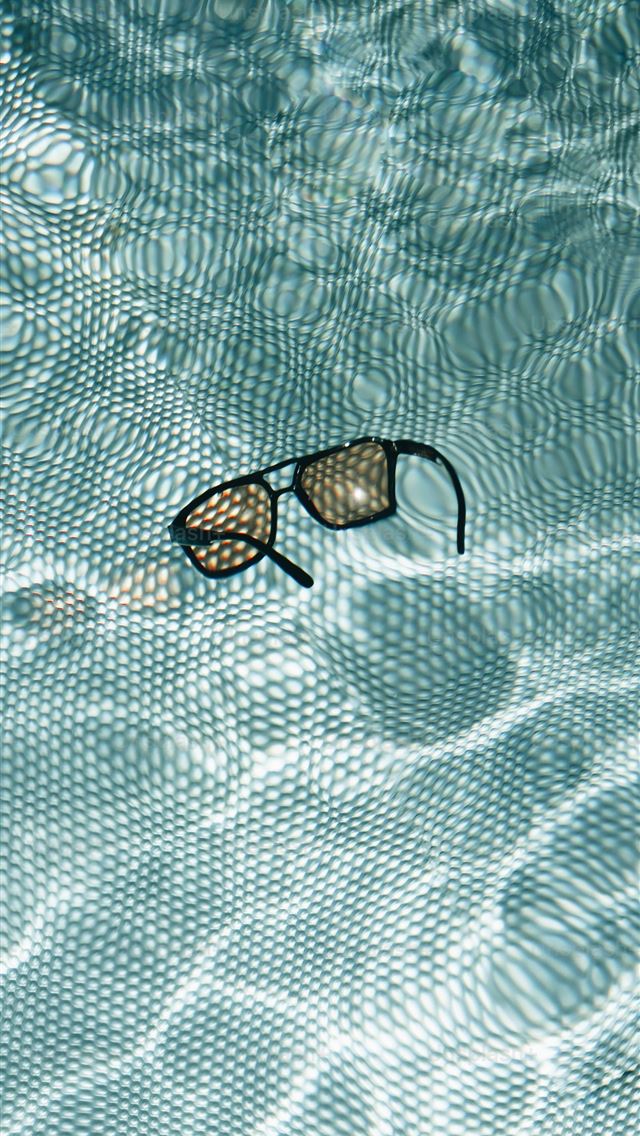 1290x2796 a pair of swimming goggles floating in a pool -  iPhone Wallpaper