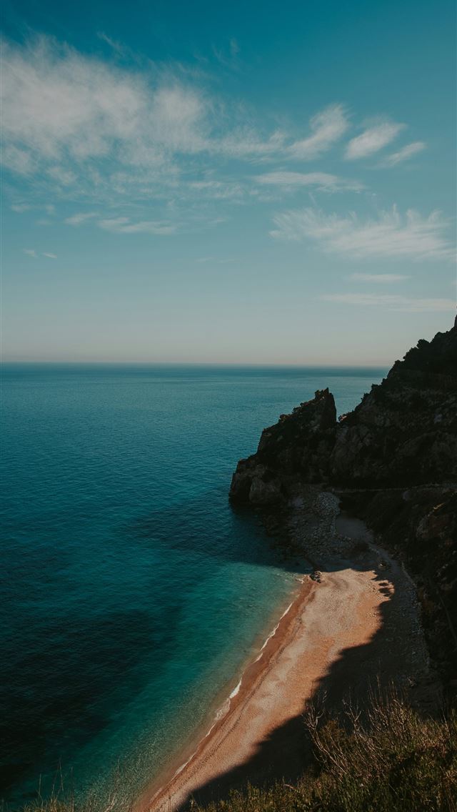 1290x2796 brown rock formation beside blue sea under blue sk... -  iPhone Wallpaper