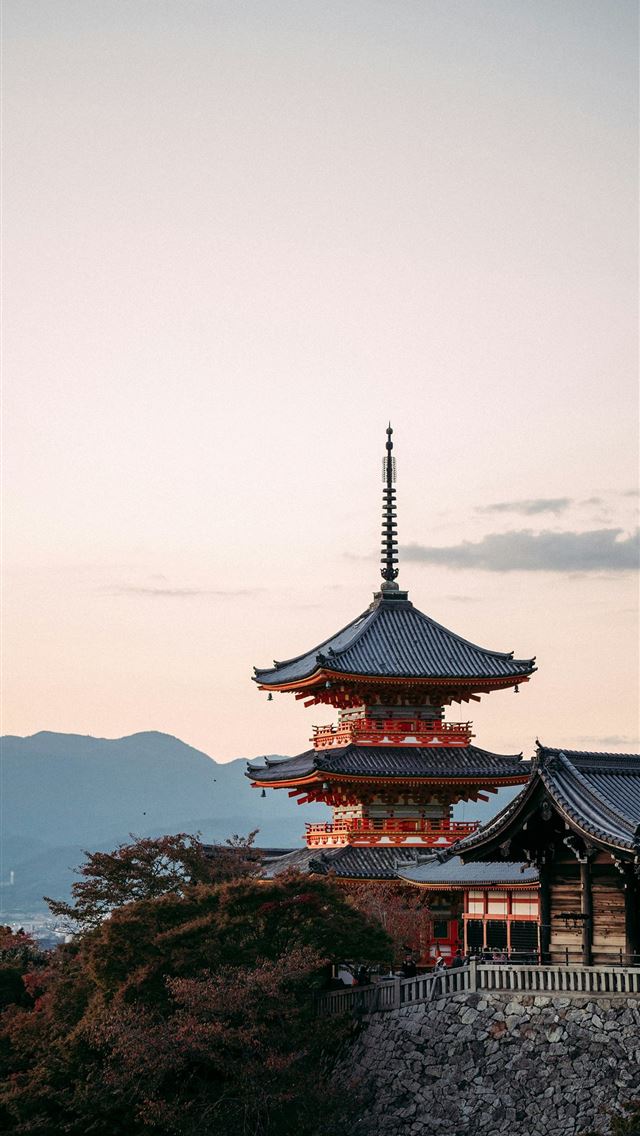 1290x2796 a tall building sitting on top of a lush green hil... -  iPhone Wallpaper