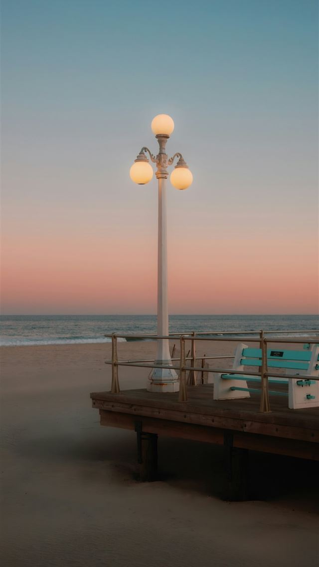 1290x2796 a light pole sitting on top of a pier next to the ... -  iPhone Wallpaper