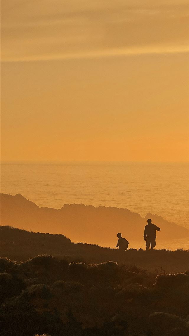 1290x2796 a couple of people standing on top of a rocky beac... -  iPhone Wallpaper