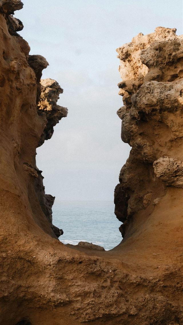 1290x2796 a couple of large rocks sitting on top of a beach -  iPhone Wallpaper