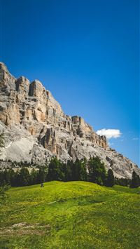 A grassy field with a mountain in the background wallpaper