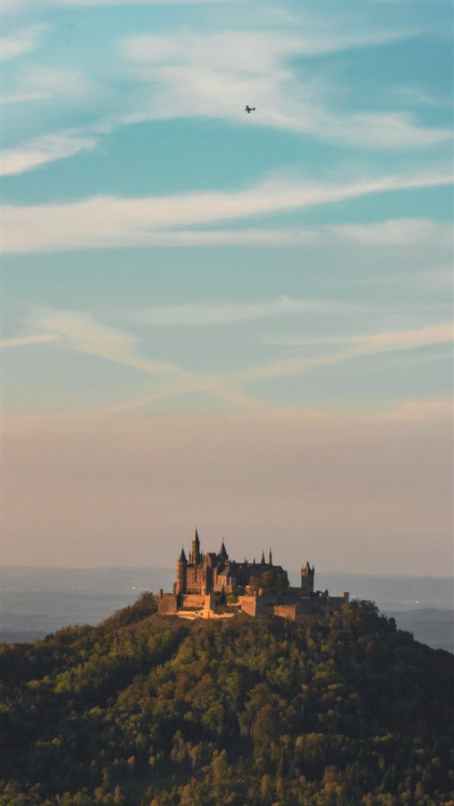 1290x2796 a castle sitting on top of a lush green hillside -  iPhone Wallpaper