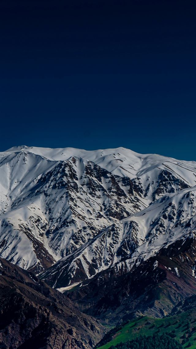 1290x2796 a snowy mountain range with a green valley below -  iPhone Wallpaper