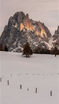 a snow covered field with trees and mountains in t... wallpaper