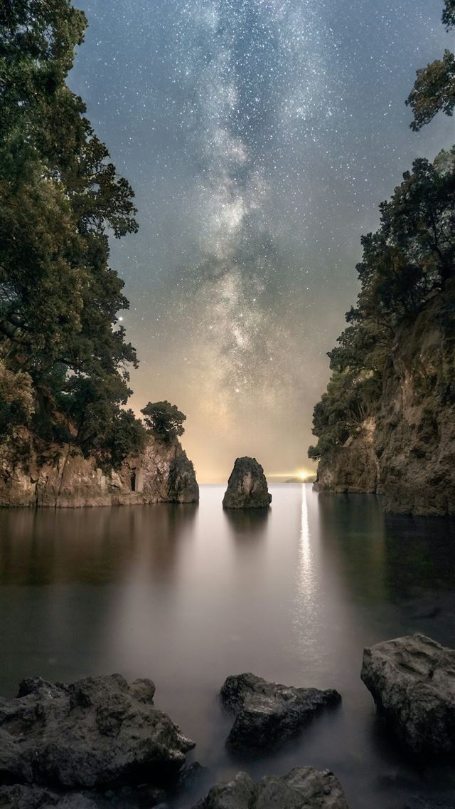 1290x2796 a body of water surrounded by rocks under a night ... - beach iPhone Wallpaper