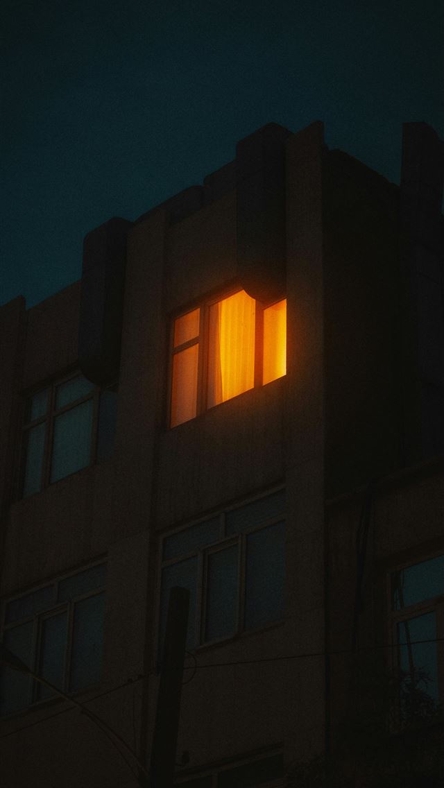 1290x2796 Building window glowing with warm orange light at ... - architecture iPhone Wallpaper