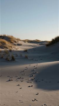 a trail of footprints in the sand of a beach wallpaper