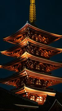 a tall building lit up at night with a sky backgro... wallpaper