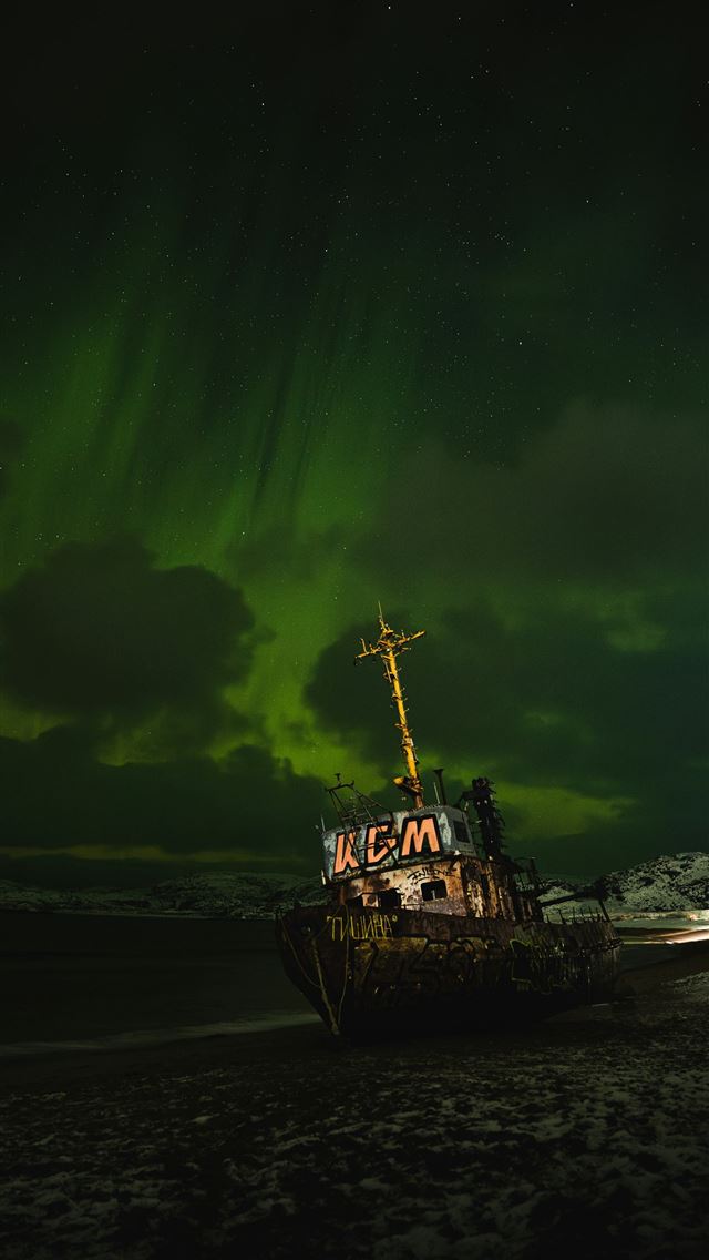 1290x2796 a boat sitting on top of a sandy beach under a gre... -  iPhone Wallpaper