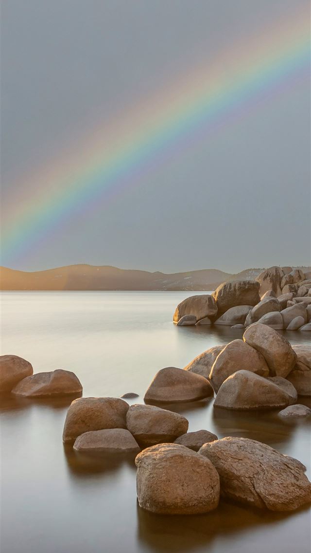 1290x2796 a rainbow shines in the sky over a body of water -  iPhone Wallpaper