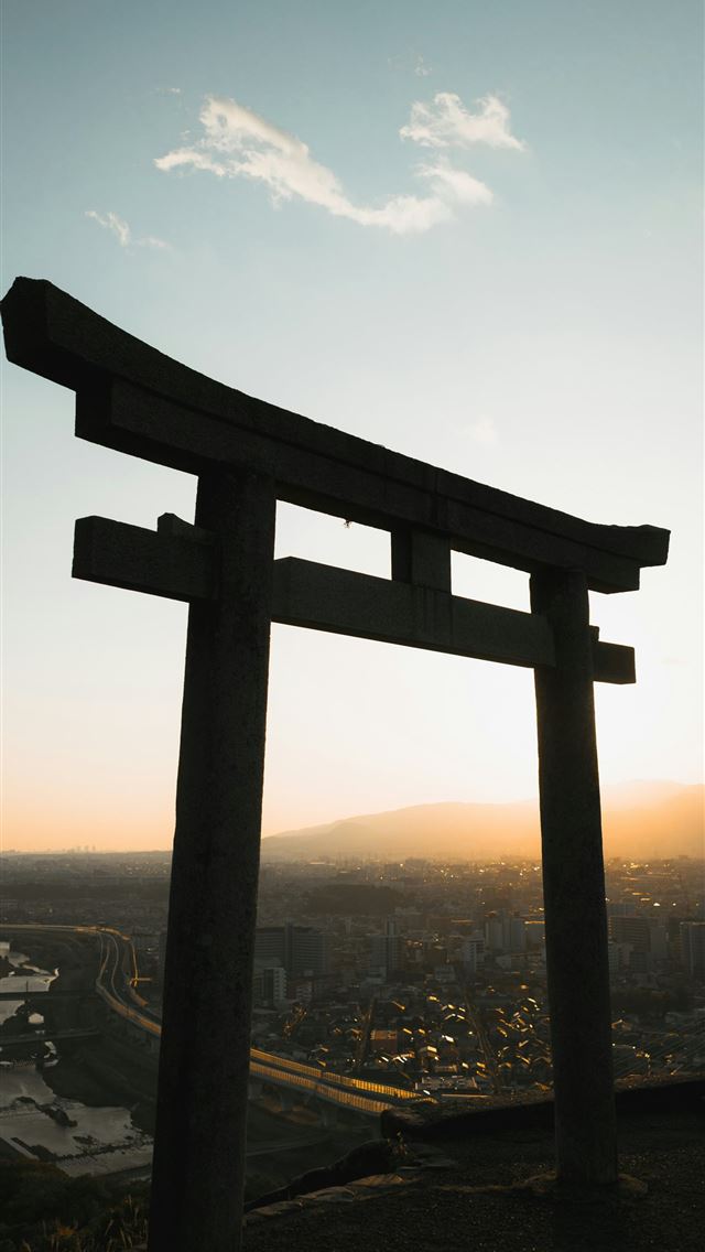 1290x2796 Torii gate silhouetted against a sunset over a cit... - tourism iPhone Wallpaper