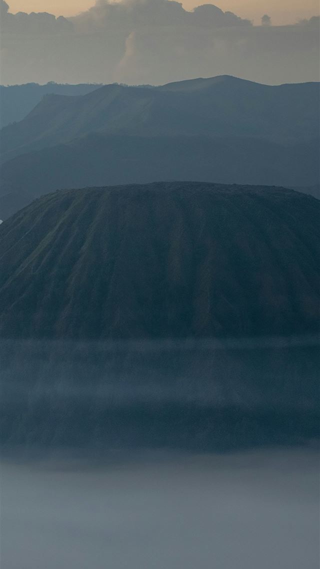 1290x2796 an airplane flying over a mountain covered in fog -  iPhone Wallpaper