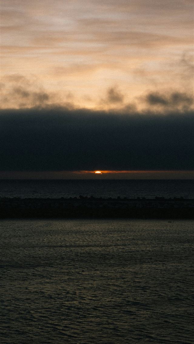 1290x2796 Sunset over a dark ocean with clouds -  iPhone Wallpaper