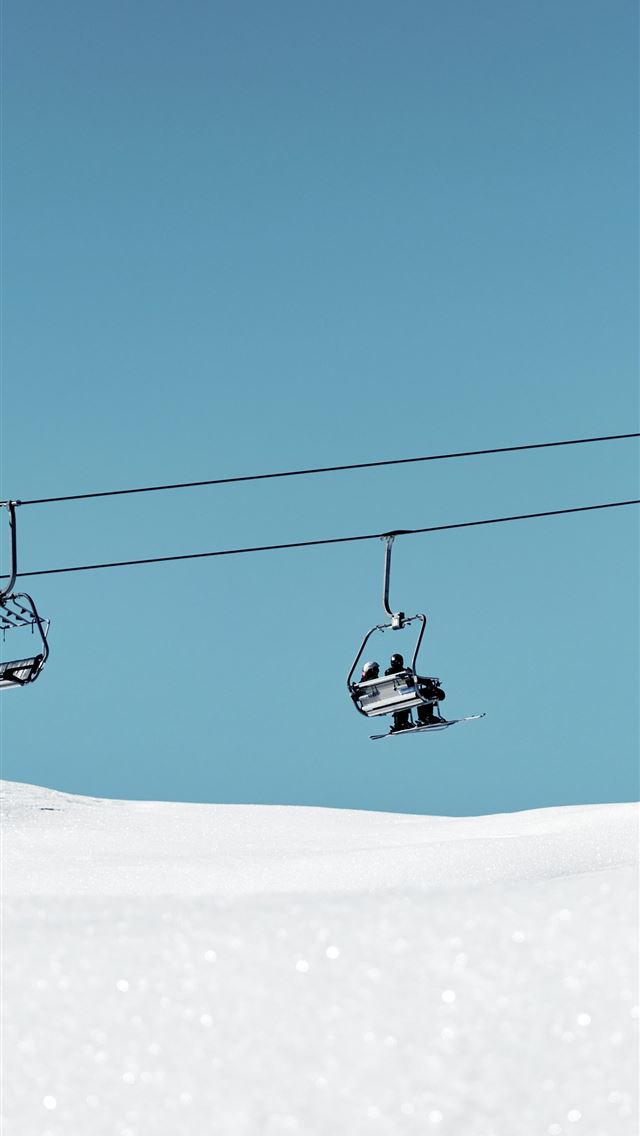 1290x2796 a ski lift with two skiers going up a snowy hill - outdoors iPhone Wallpaper