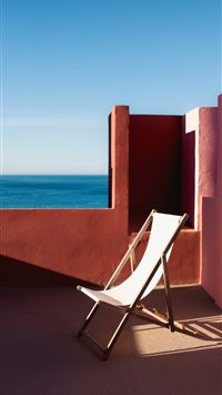 a white chair sitting on top of a balcony next to ... wallpaper
