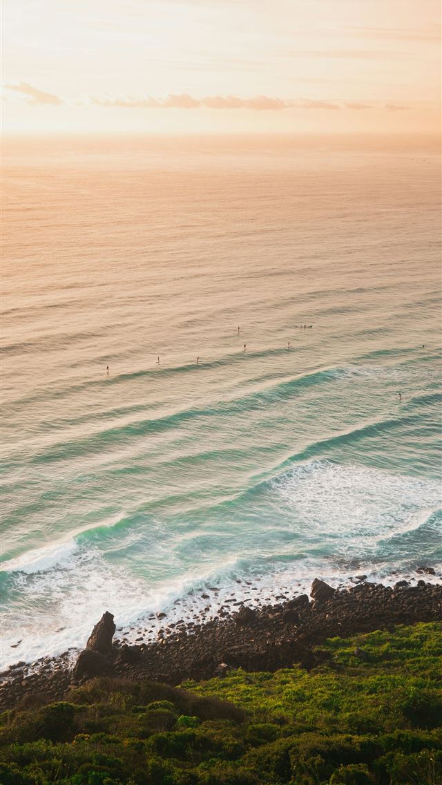 1290x2796 green grass on brown rock formation beside body of... - Travel iPhone Wallpaper