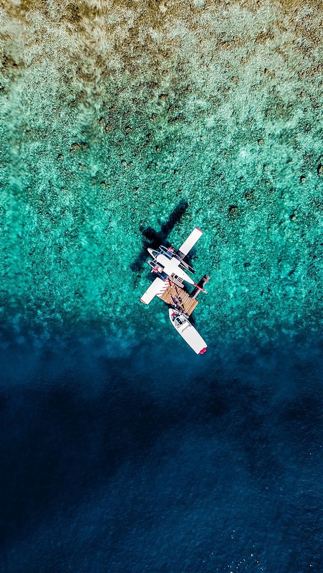 1290x2796 an aerial view of a plane flying over a body of wa... - airplane iPhone Wallpaper