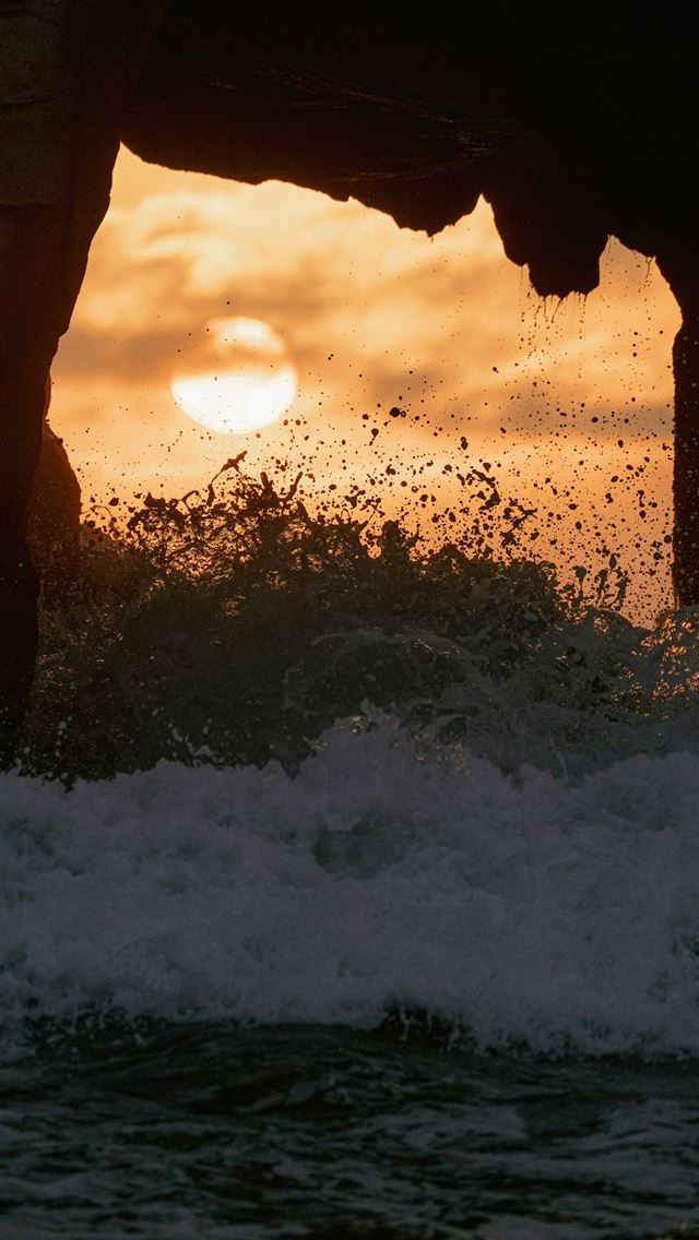 1290x2796 Sunset viewed through a rock arch with ocean waves... -  iPhone Wallpaper