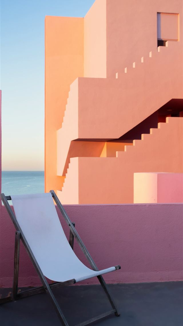 1290x2796 a white chair sitting in front of a pink building -  iPhone Wallpaper