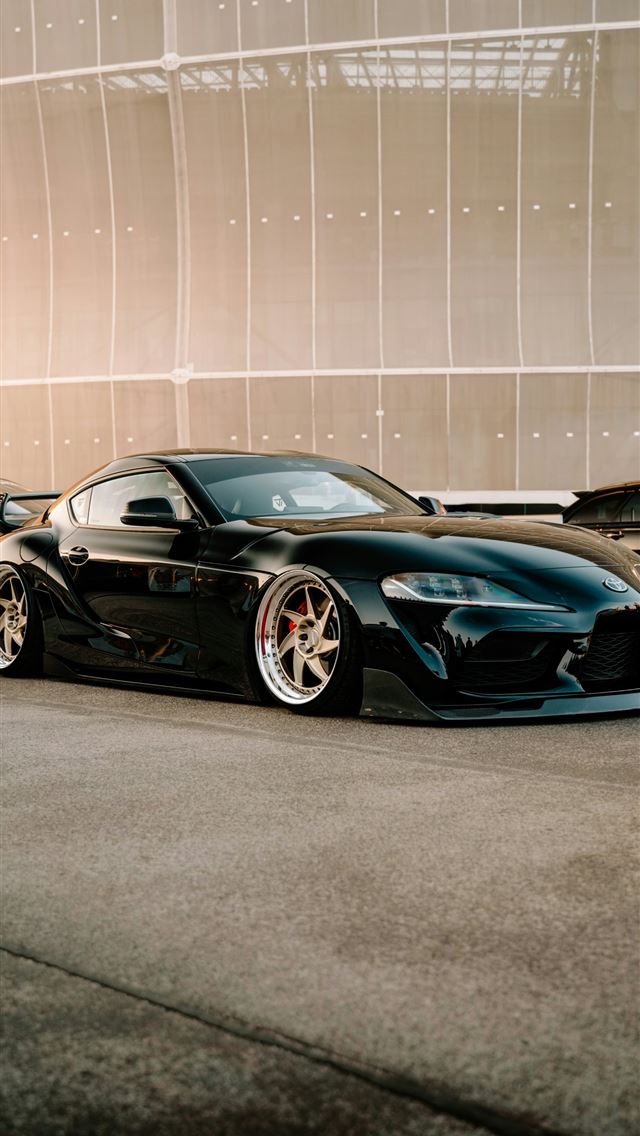 1290x2796 a black sports car parked in front of a building -  iPhone Wallpaper