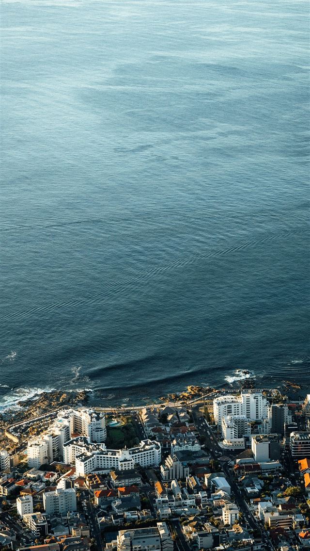 1290x2796 an aerial view of a city by the ocean - sunset iPhone Wallpaper