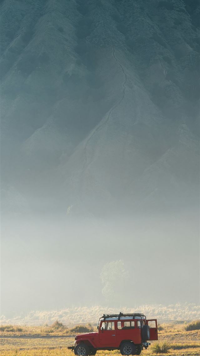 1290x2796 a red truck driving down a road next to a mountain -  iPhone Wallpaper