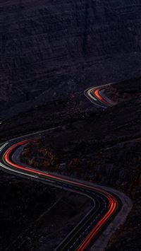 a winding road in the mountains at night wallpaper
