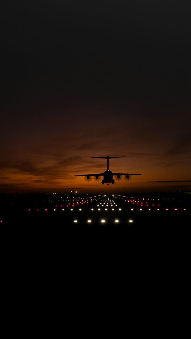 1290x2796 a large jetliner flying over a runway at night -  iPhone Wallpaper