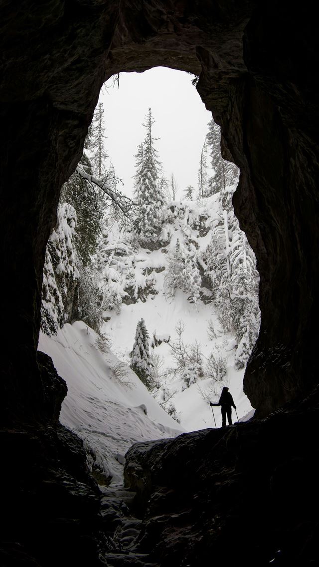 1290x2796 Person standing at cave entrance overlooking snowy... -  iPhone Wallpaper