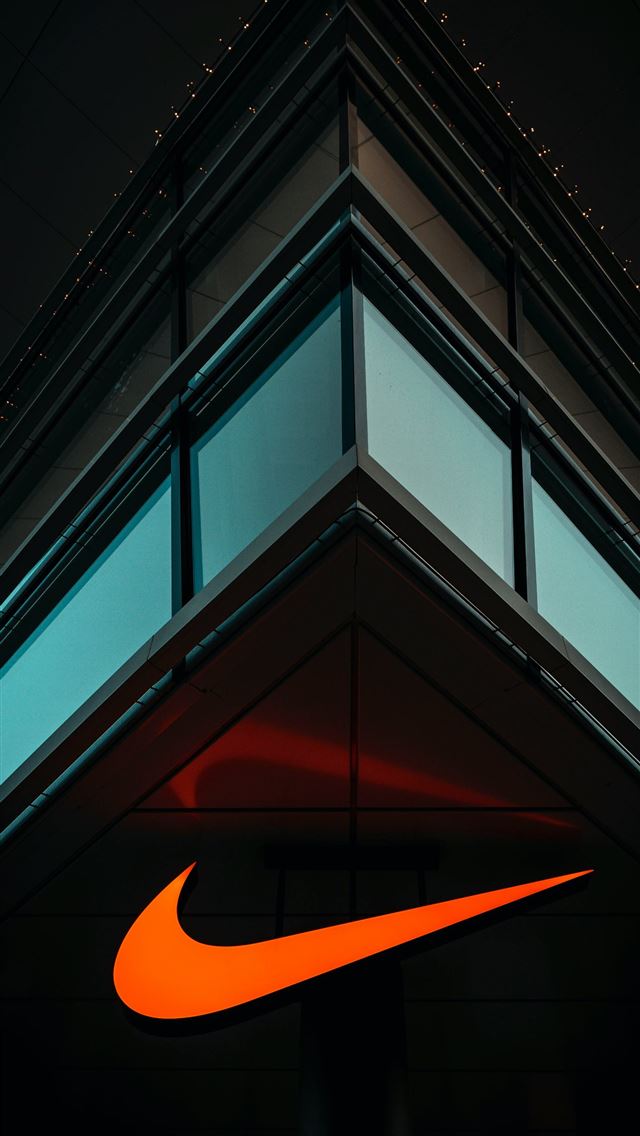 1290x2796 the nike logo is lit up on the side of a building -  iPhone Wallpaper