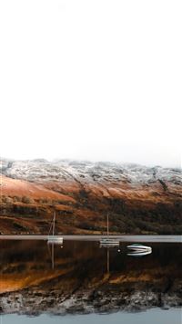 a boat on a lake with mountains in the background wallpaper