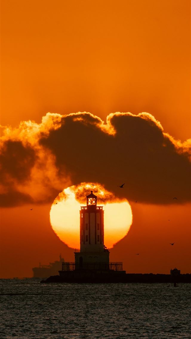 1290x2796 the sun is setting behind a lighthouse in the ocea... - usa iPhone Wallpaper