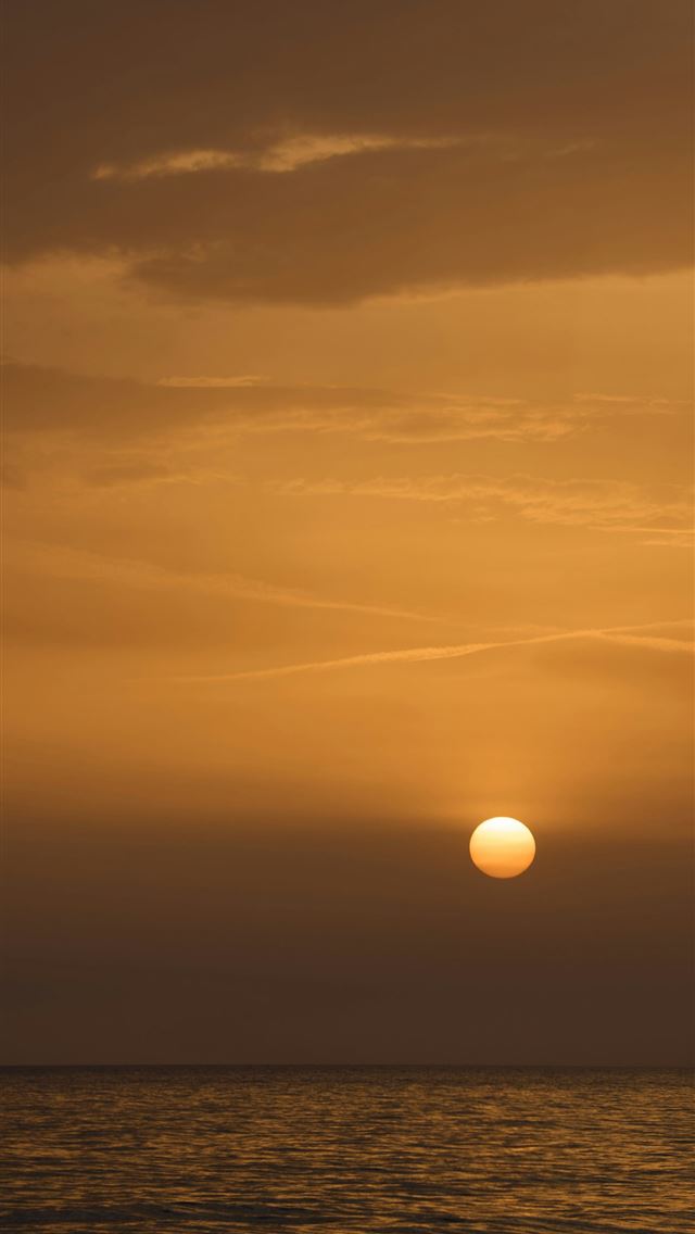 1290x2796 the sun is setting over the ocean on a cloudy day -  iPhone Wallpaper