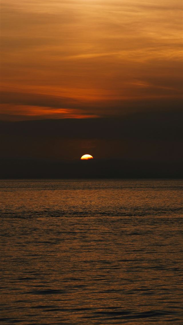 1290x2796 the sun is setting over the ocean on a cloudy day - lisbon iPhone Wallpaper