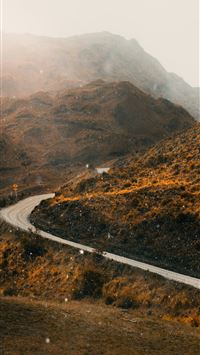 a winding road in the mountains on a foggy day wallpaper