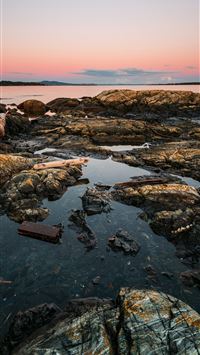 a body of water sitting on top of a rocky beach wallpaper