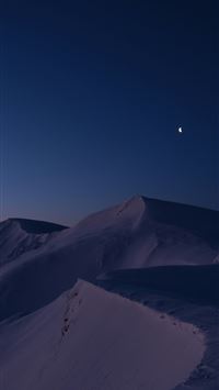 Snowy mountain range under a dark blue twilight sk... wallpaper
