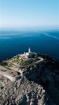 a lighthouse on a rocky outcropping in the middle ... wallpaper