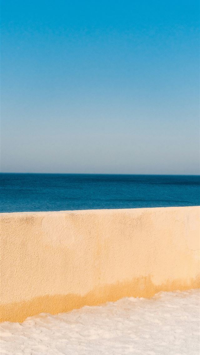 1290x2796 A clear blue sky over a calm ocean and wall -  iPhone Wallpaper