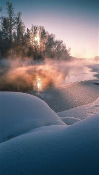 Misty river flows through a snowy forest at sunris... wallpaper
