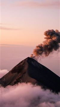 Volcano erupting smoke above clouds at sunset wallpaper