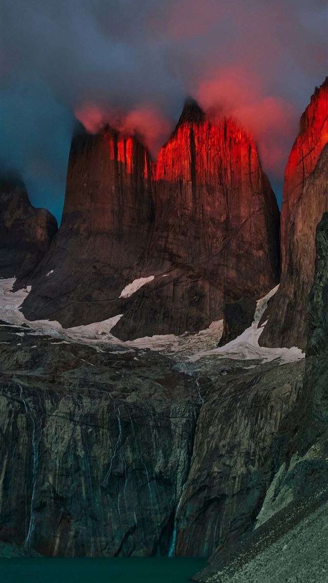 1290x2796 Red glow illuminates rugged mountain peaks above a... -  iPhone Wallpaper