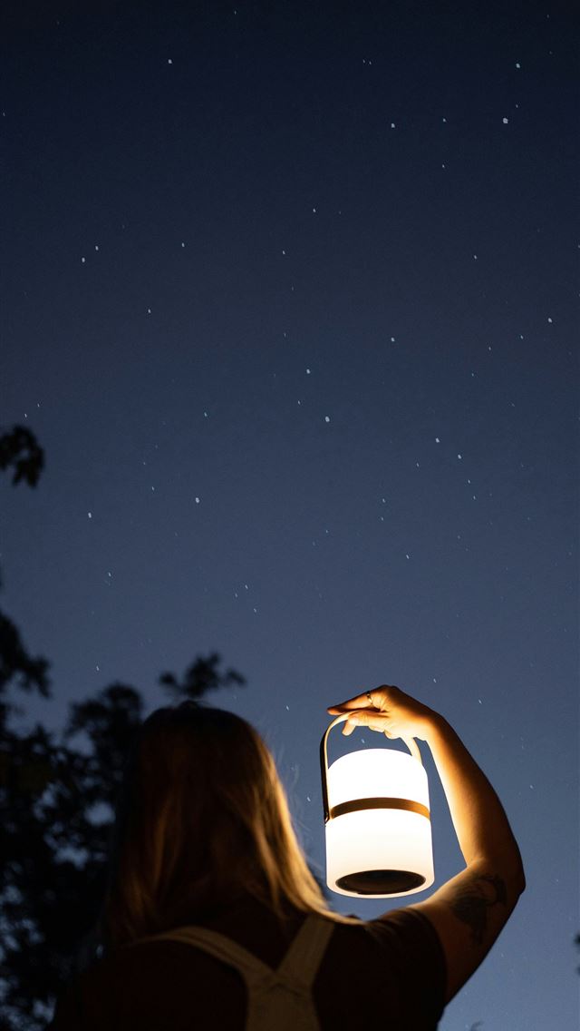 1290x2796 a woman is holding a lantern in the dark -  iPhone Wallpaper